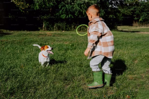 boy playing in grass with pet dog